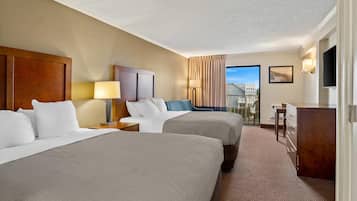 A hotel room with two beds, a desk, a chair, a lamp, and a TV.