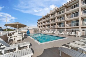 Un espace piscine d’hôtel avec des chaises longues et des parasols.