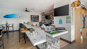 A restaurant with a bar area, wooden chairs, tables, and a surfboard on the wall. - Quality Inn & Suites Ocean City Fenwick (Ocean City)