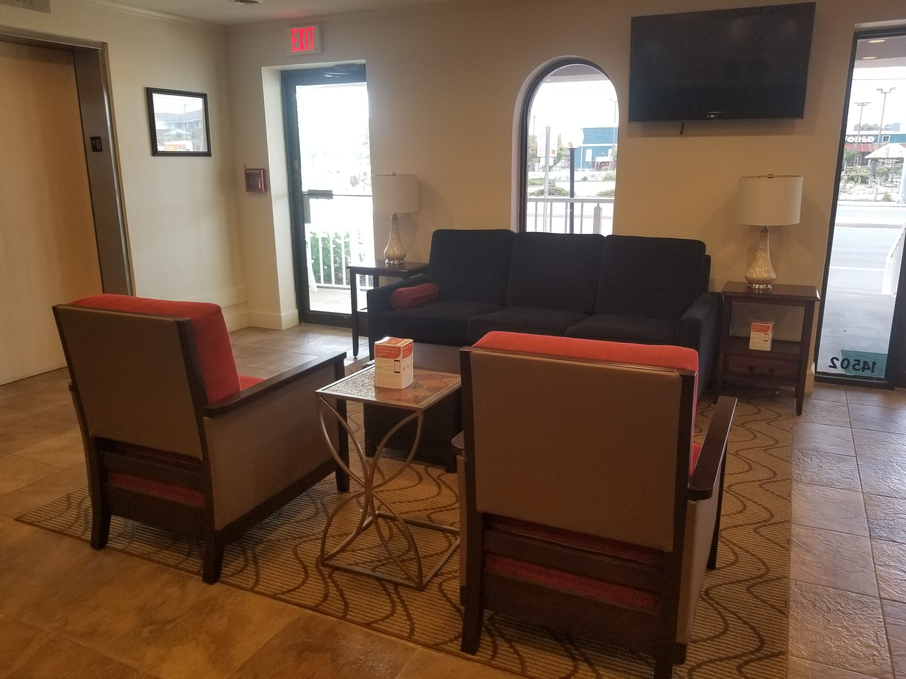 Un hall d’entrée avec un canapé, deux fauteuils, une petite table, une lampe et un téléviseur.
