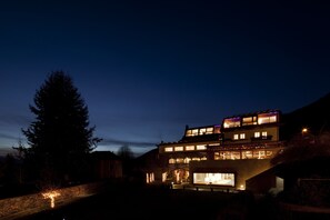 A modern two-story building with multiple windows and a well-lit entrance. - Hotel Milano Alpen Resort (Castione della Presolana)