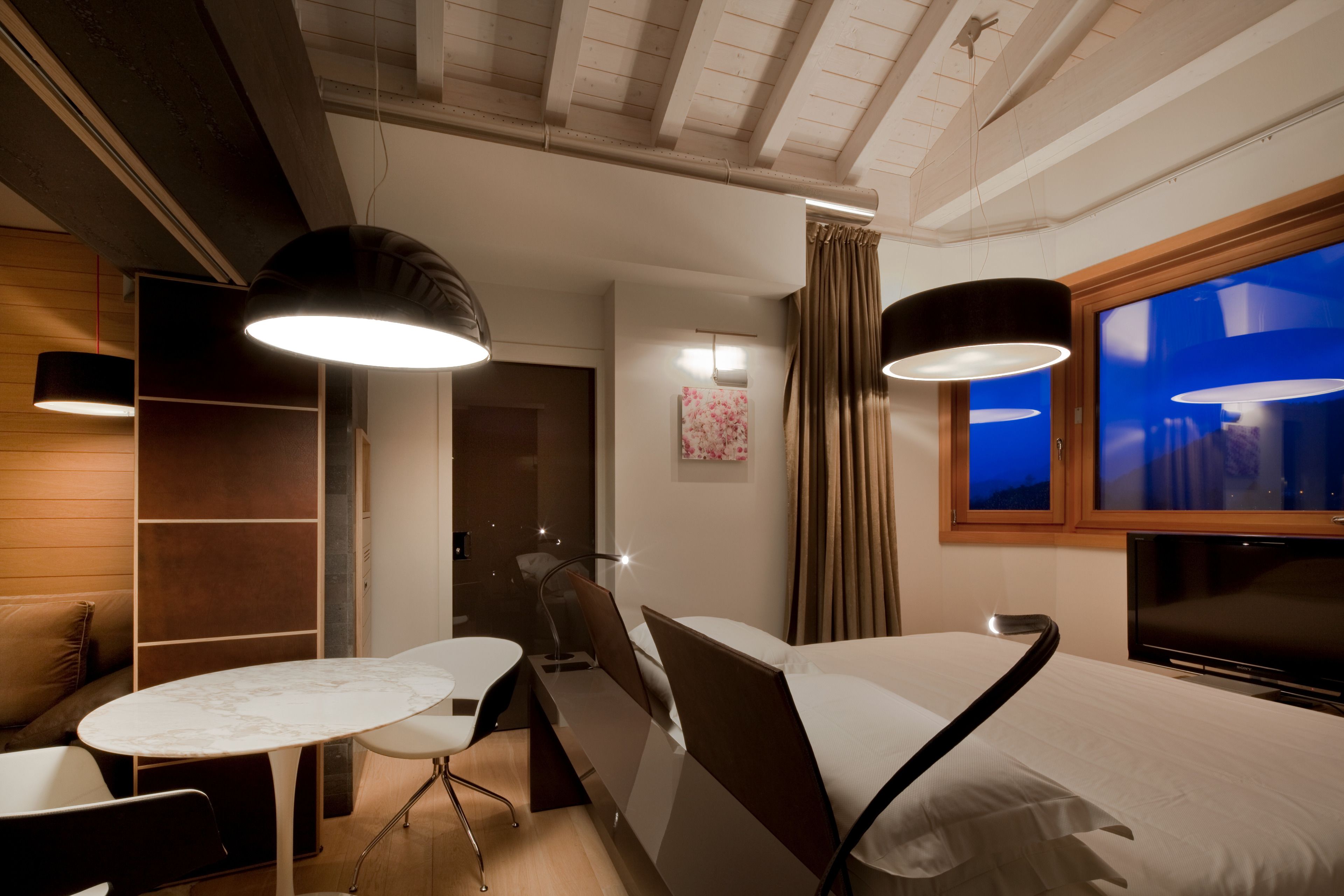Une chambre d’hôtel moderne équipée d’un lit, d’un bureau, d’une chaise et d’un téléviseur.