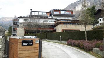 A modern building with a wooden facade, a sign indicating destination charging, and a view of mountains in the background.