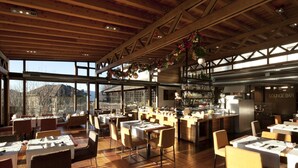 Un restaurant ampli amb terres i taules de fusta, grans finestres que ofereixen vista a les muntanyes, i una zona de bar-saló.