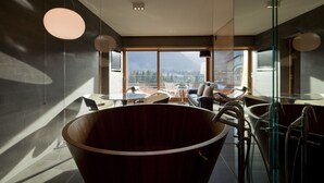 Un interior modern amb una àrea d'seure gran de fusta, separadors de vidre i vista a les muntanyes a través de grans finestres.