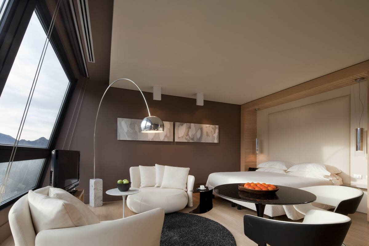 Una habitación de hotel moderna con una cama grande, un sofá, una mesa de comedor y un televisor.