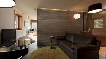 A modern living room with a glass table, a leather sofa, and a round rug.