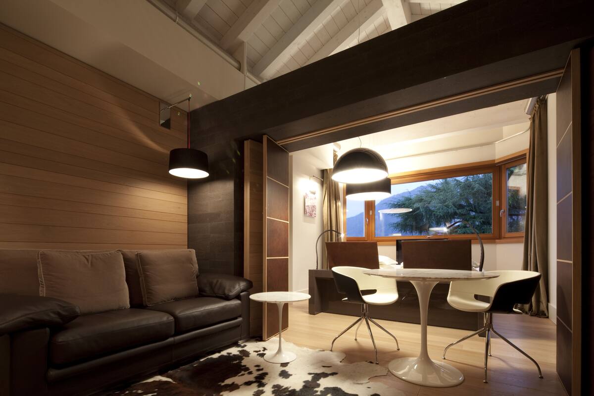 Una sala de estar moderna con un sofá de cuero, una mesa de centro redonda y un comedor con una mesa y sillas blancas.