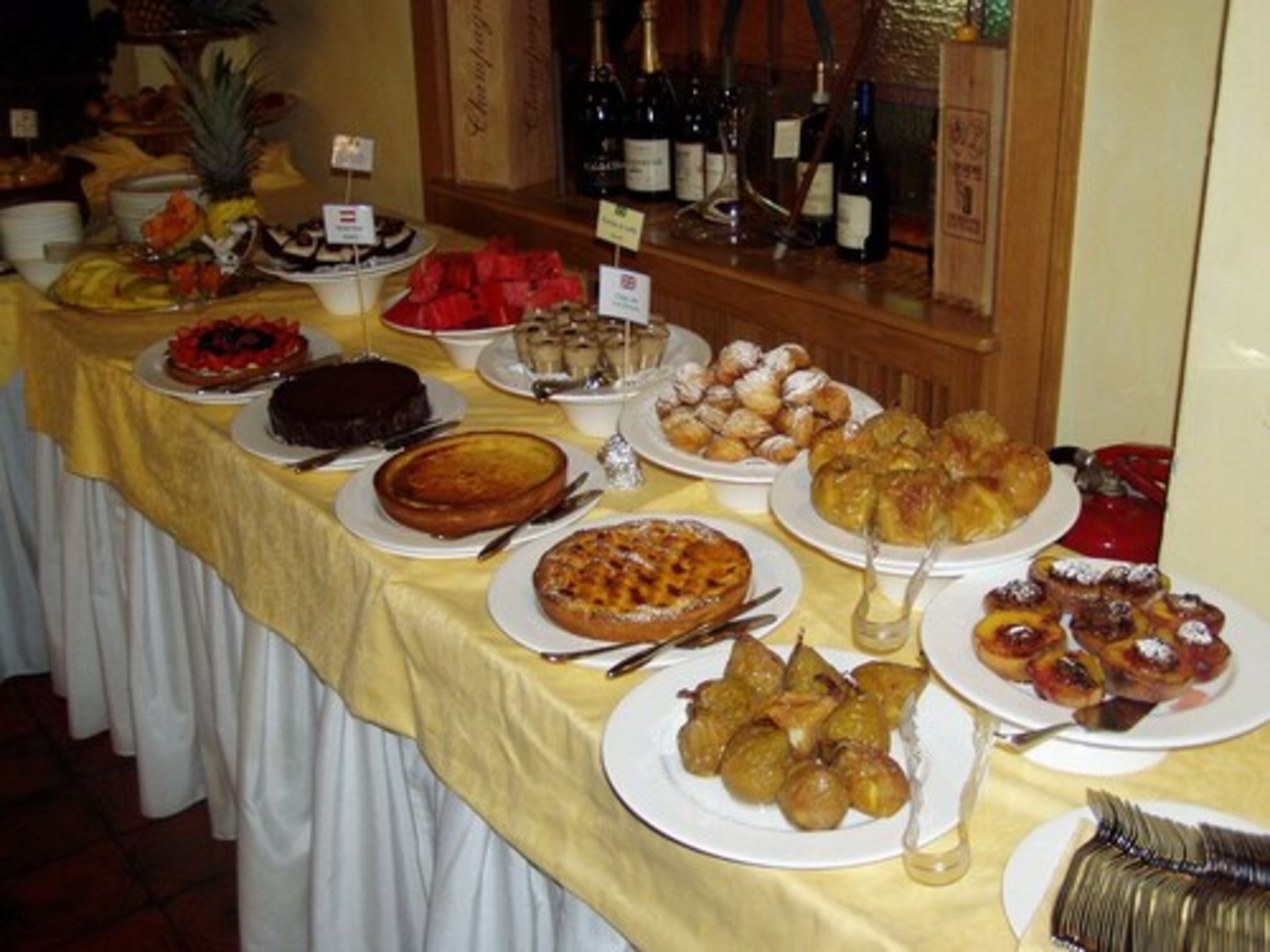 Una mesa de buffet con diversos platos, entre ellos pasteles, bollos y frutas.
