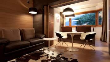 A modern living room with a leather sofa, a round coffee table, and a dining area with a white table and black chairs.
