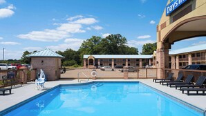 A Days Inn with a swimming pool, lounge chairs, and a fenced parking area. - Days Inn by Wyndham Conway (Conway)