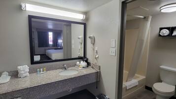 Un baño de hotel con lavamanos doble, un espejo grande, secador de pelo y zona de ducha.