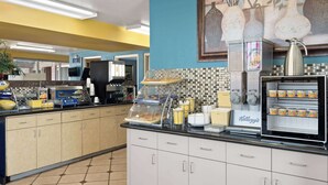 A breakfast bar with a coffee machine, a refrigerator with beverages, and a wall-mounted coffee dispenser. - Days Inn by Wyndham Conway (Conway)