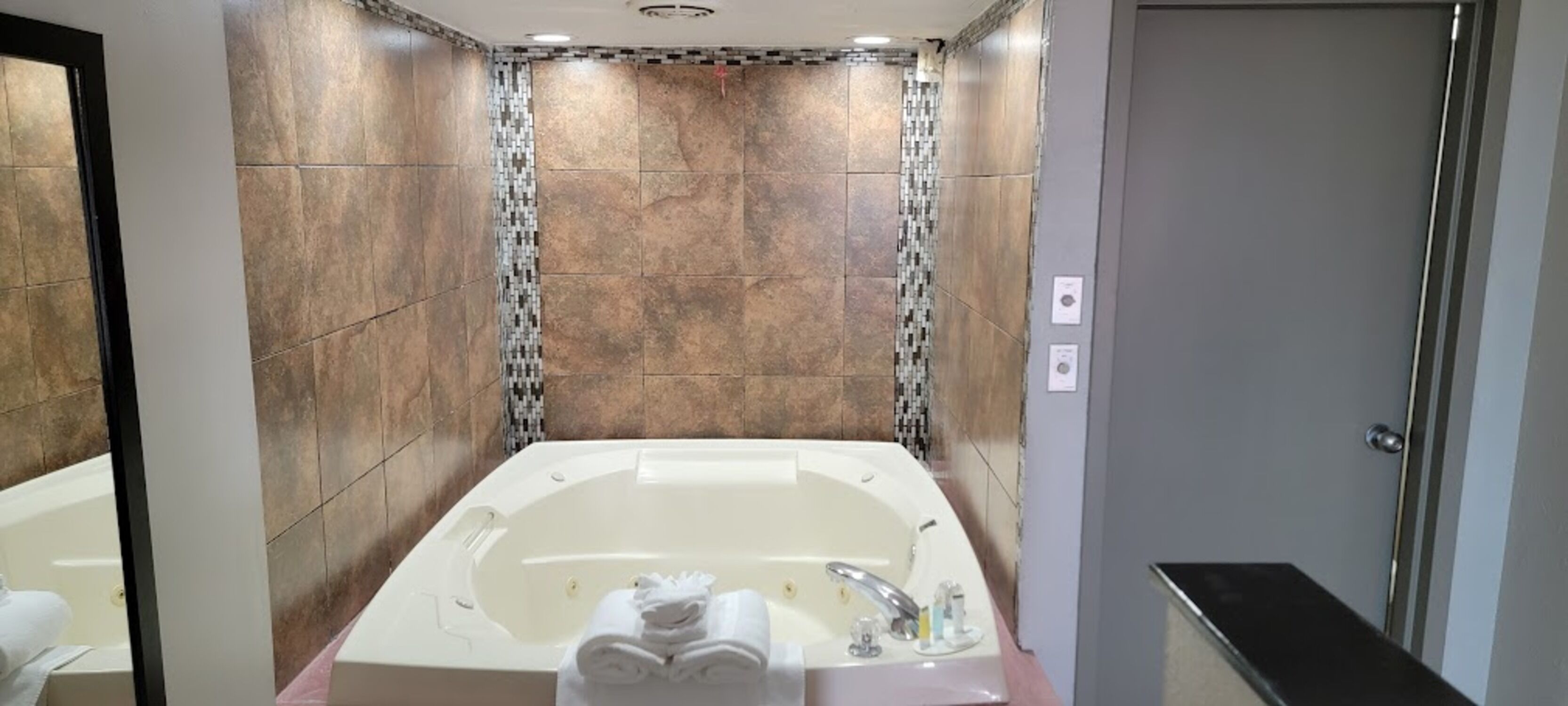 A modern bathroom with a large bathtub, tiled walls, and a shower area.
