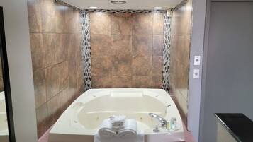 Un baño moderno con una bañera grande, paredes con azulejos y una zona de ducha.