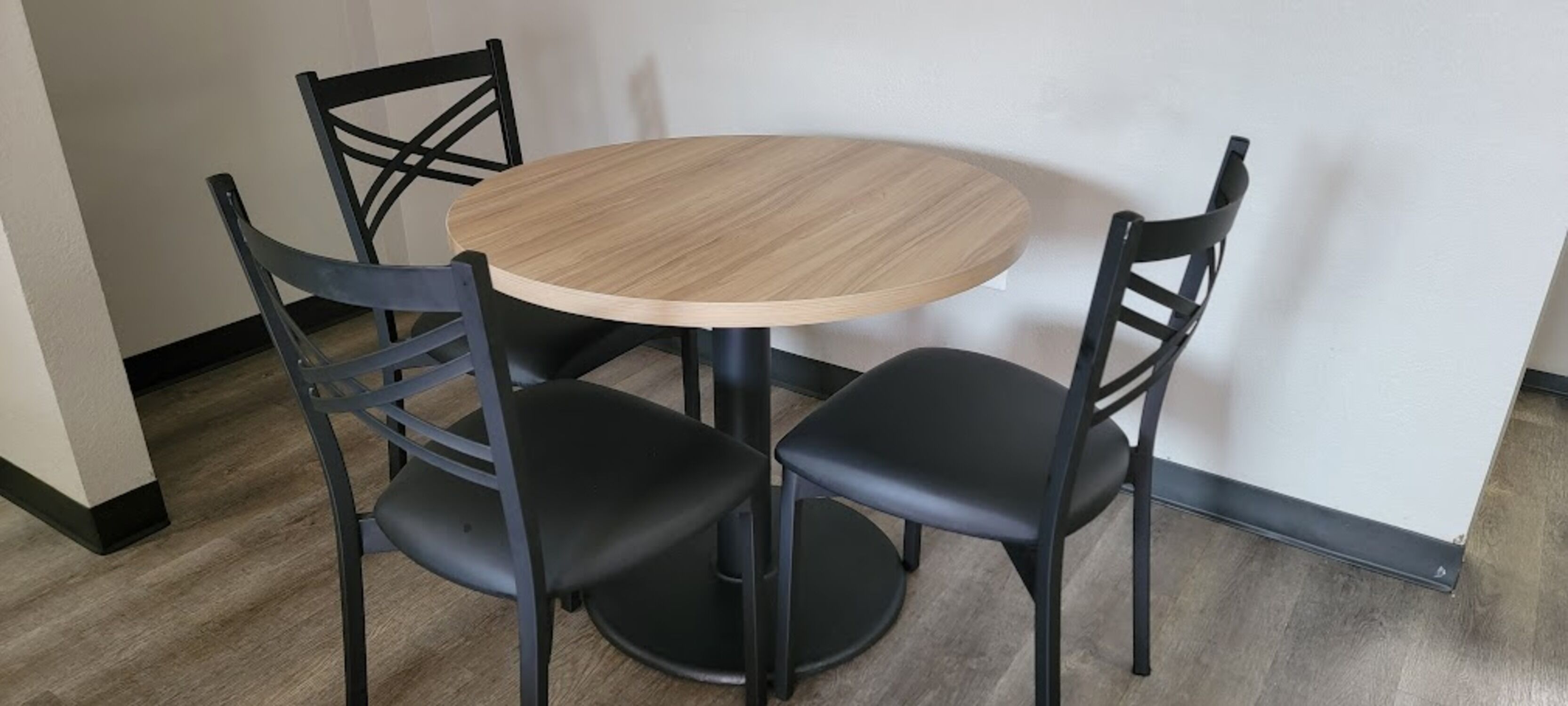 A round wooden table with four black chairs.