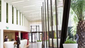 Un hall d’entrée spacieux au design moderne, comprenant un comptoir d’accueil, un espace salon et de grandes fenêtres.