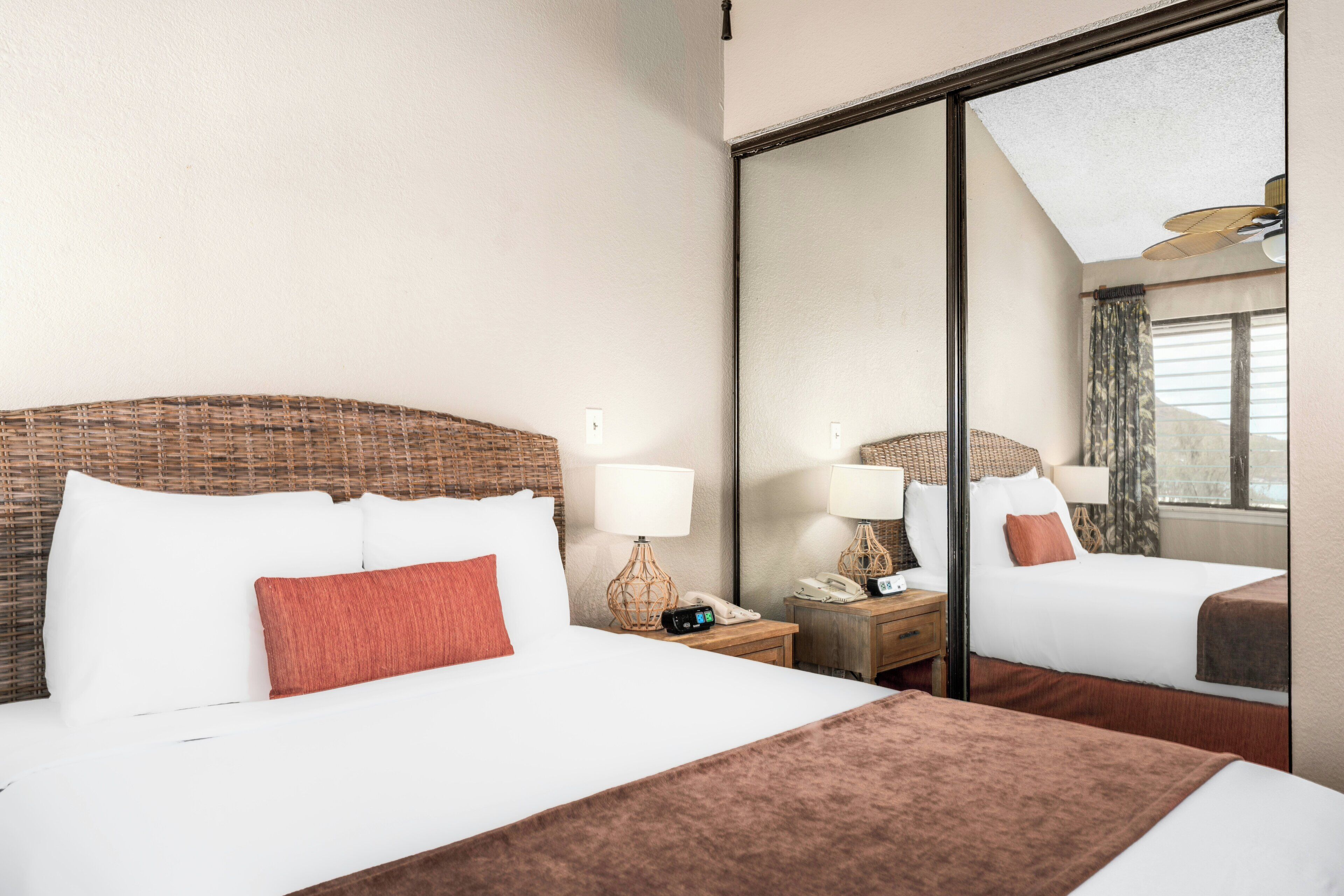 A hotel room with a large bed, two bedside tables with lamps, a mirror, and a view of the outside.