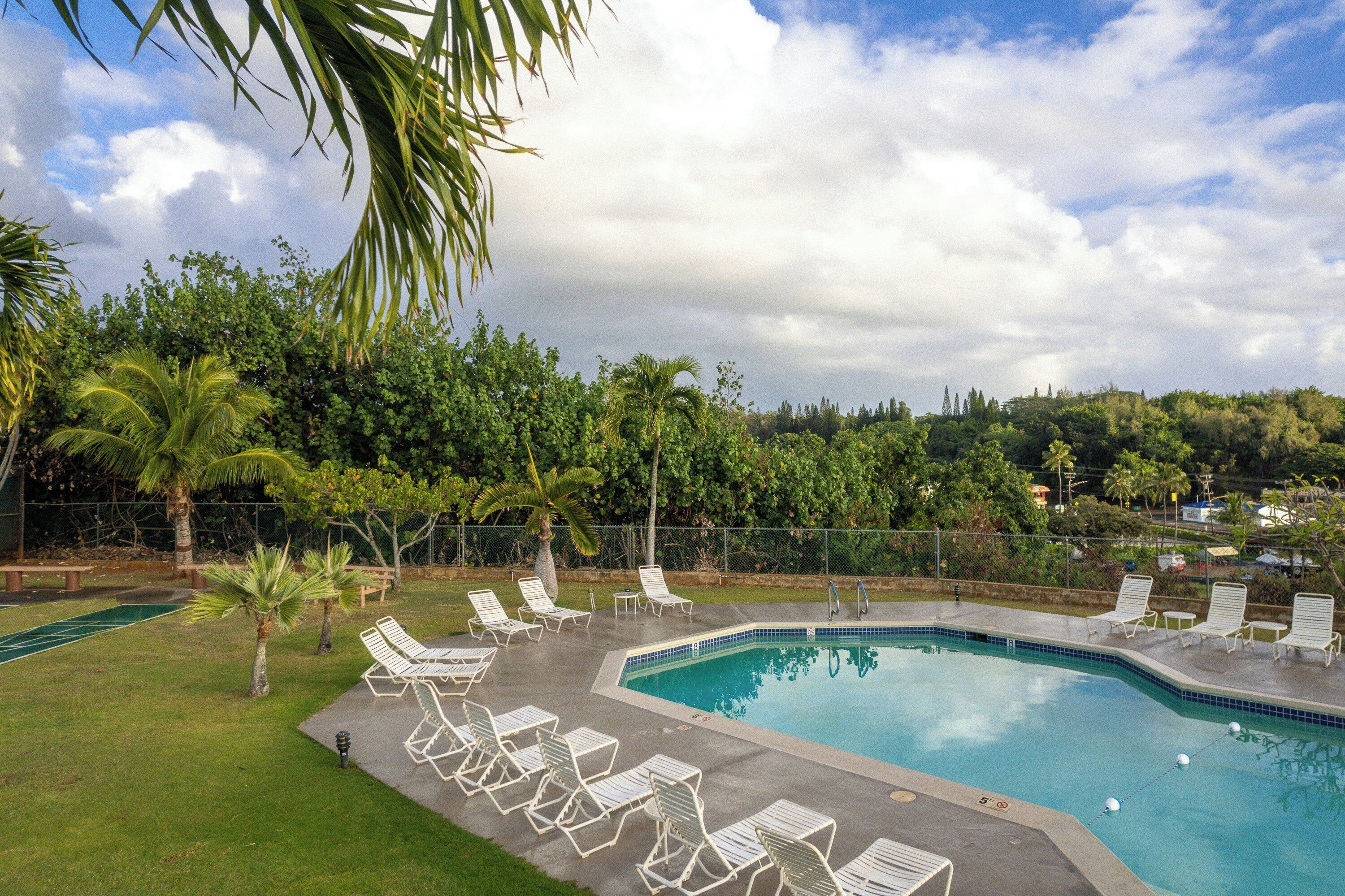 Une piscine avec des chaises longues et une pelouse.