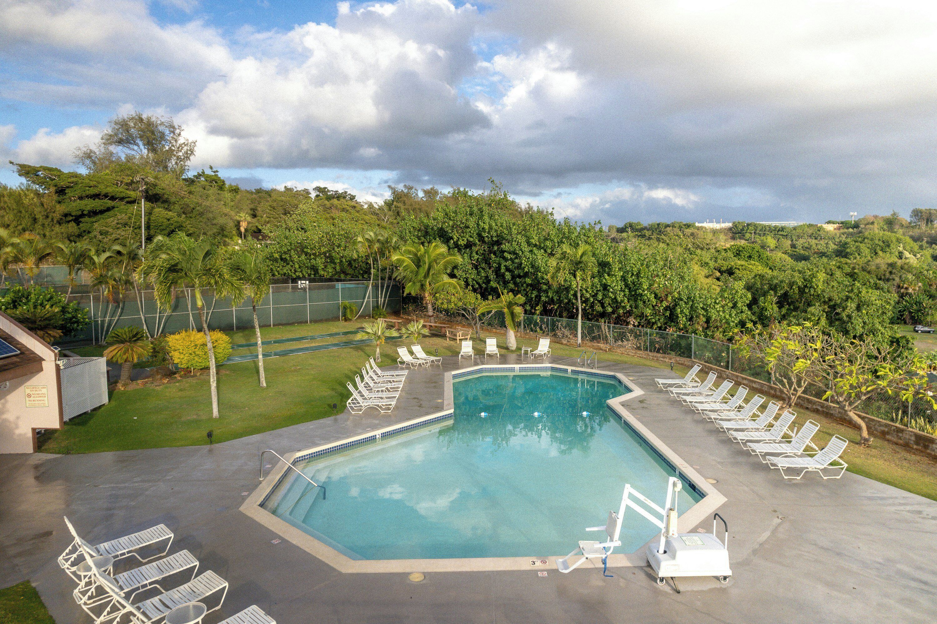 Una piscina con sillones de descanso y vistas a un paisaje verde exuberante.