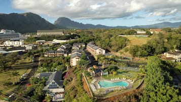 A resort with a swimming pool, solar panels, and a view of mountains.