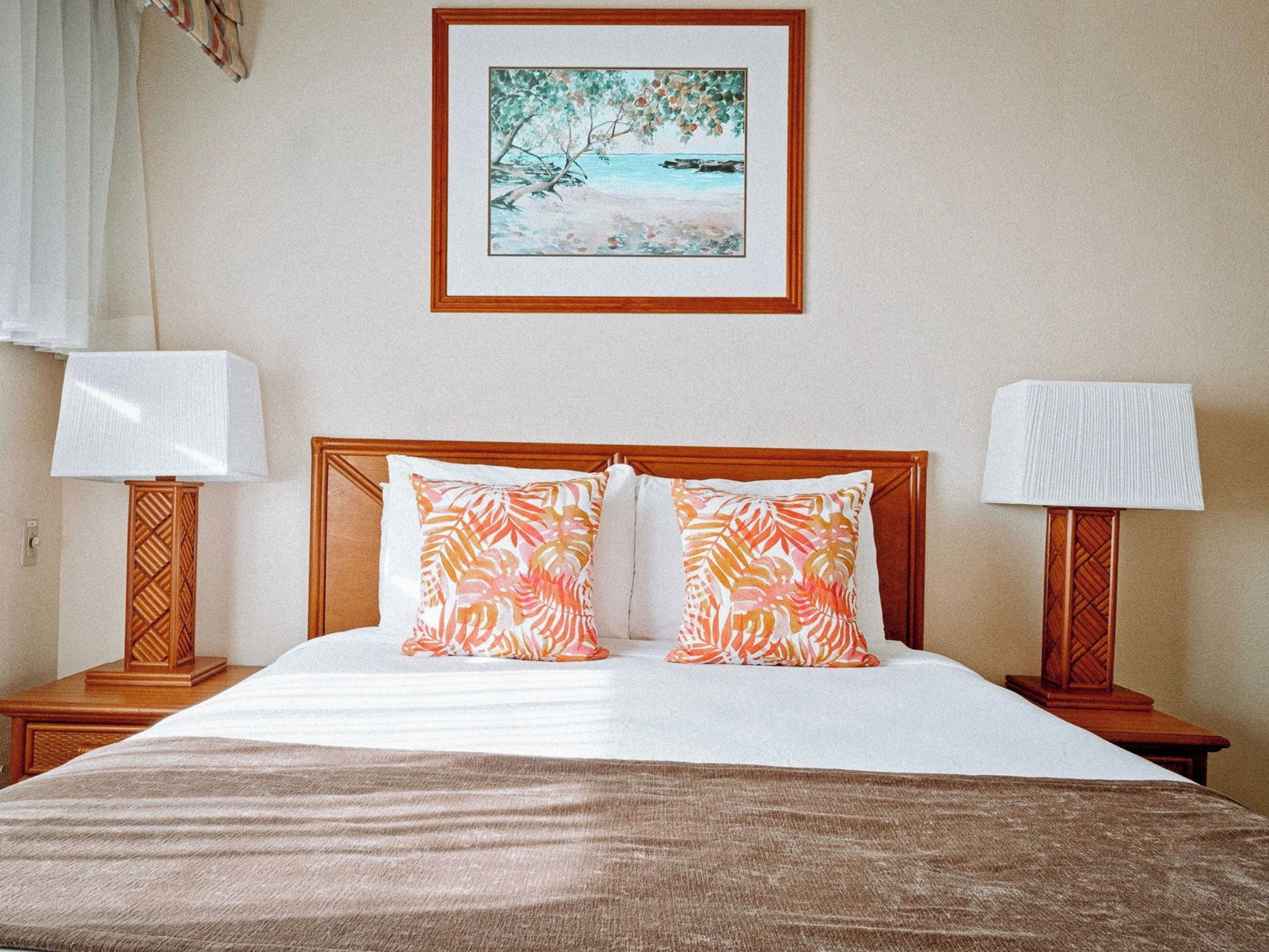 A hotel room with a bed, two nightstands, a framed picture on the wall, and a window with curtains.