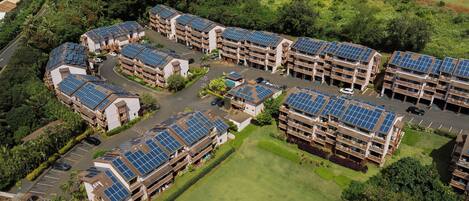 A residential complex with multiple buildings, each featuring solar panels on the roofs.