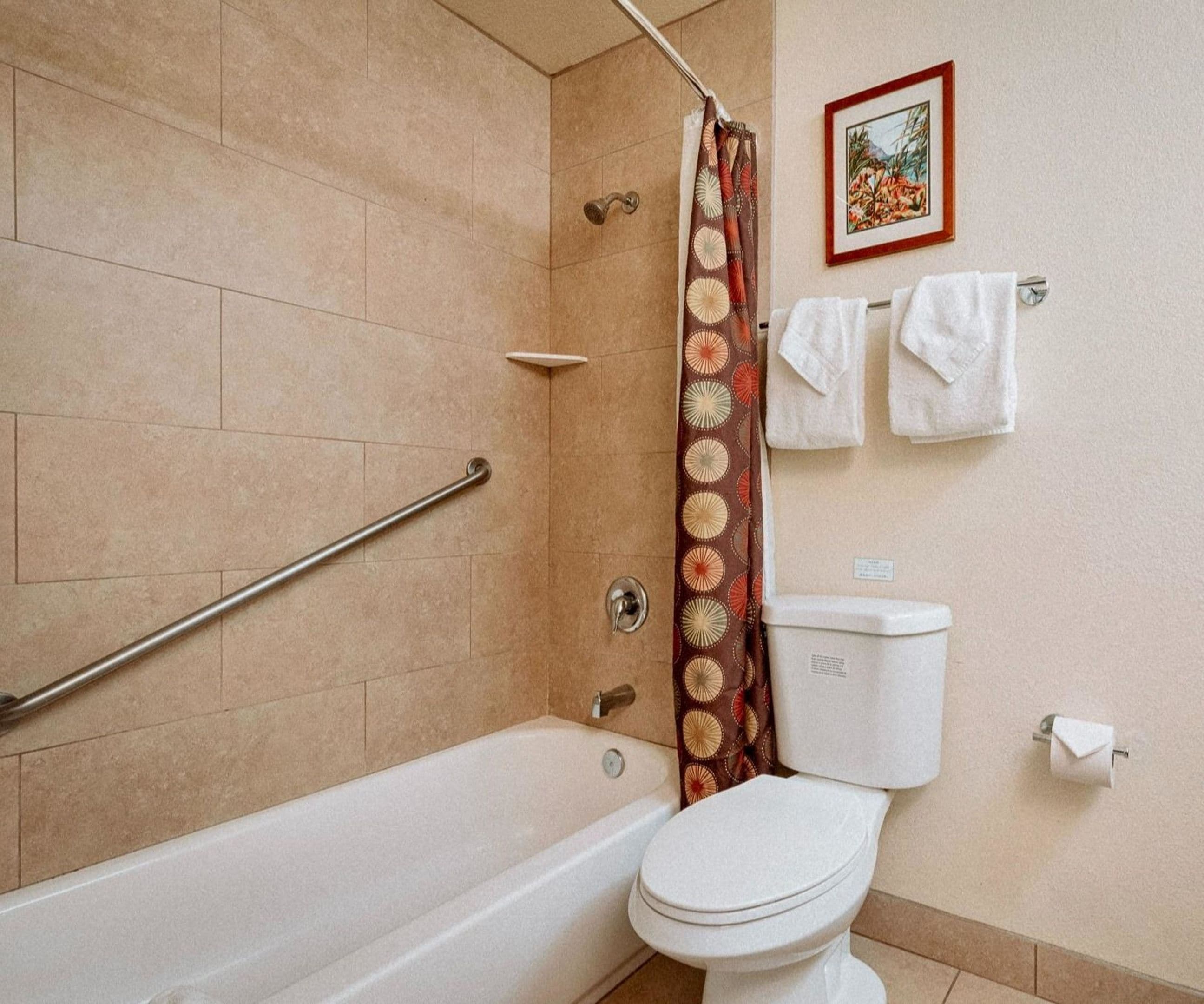 Une salle de bain équipée d’une baignoire, de toilettes, d’un rideau de douche et d’un porte-serviettes avec des serviettes.