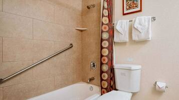 Une salle de bain équipée d’une baignoire, de toilettes, d’un rideau de douche et d’un porte-serviettes avec des serviettes.