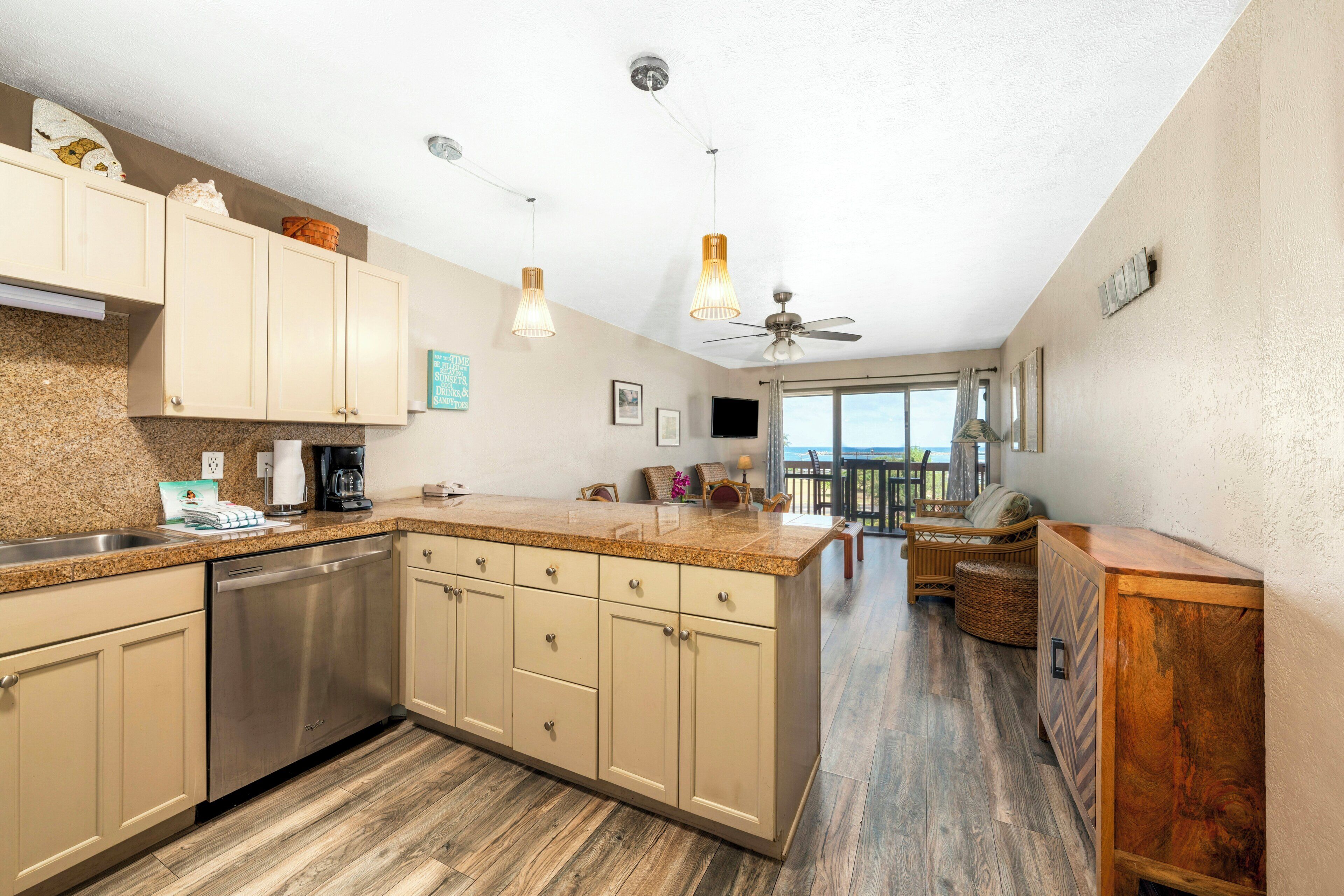 A kitchen with a central island, stainless steel appliances, and a view to a balcony.