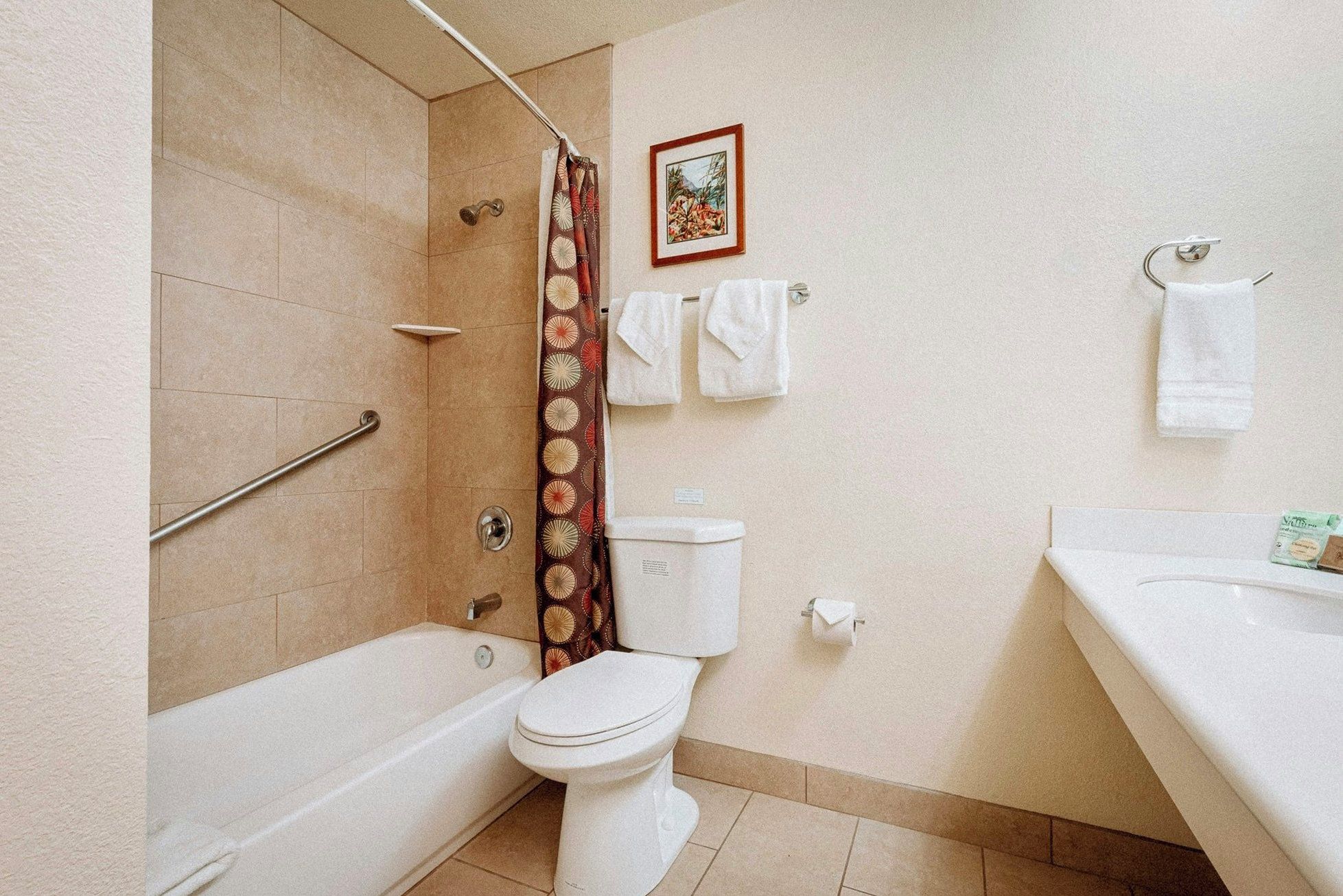 Ein Badezimmer mit Badewanne, Toilette, Duschvorhang und einem Handtuchhalter mit Handtüchern.