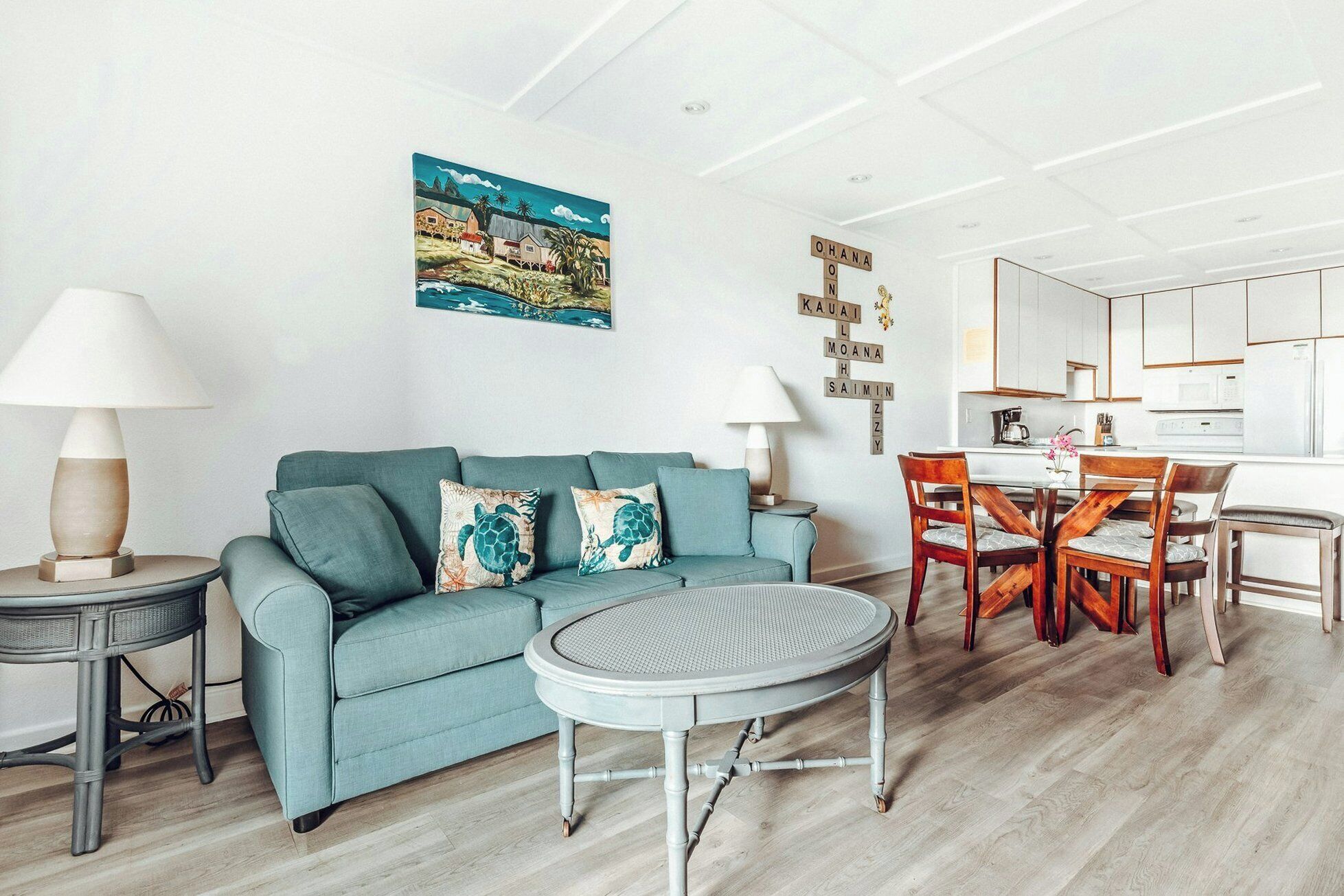 A living room with a sofa, a round coffee table, and a dining area with chairs and a table.