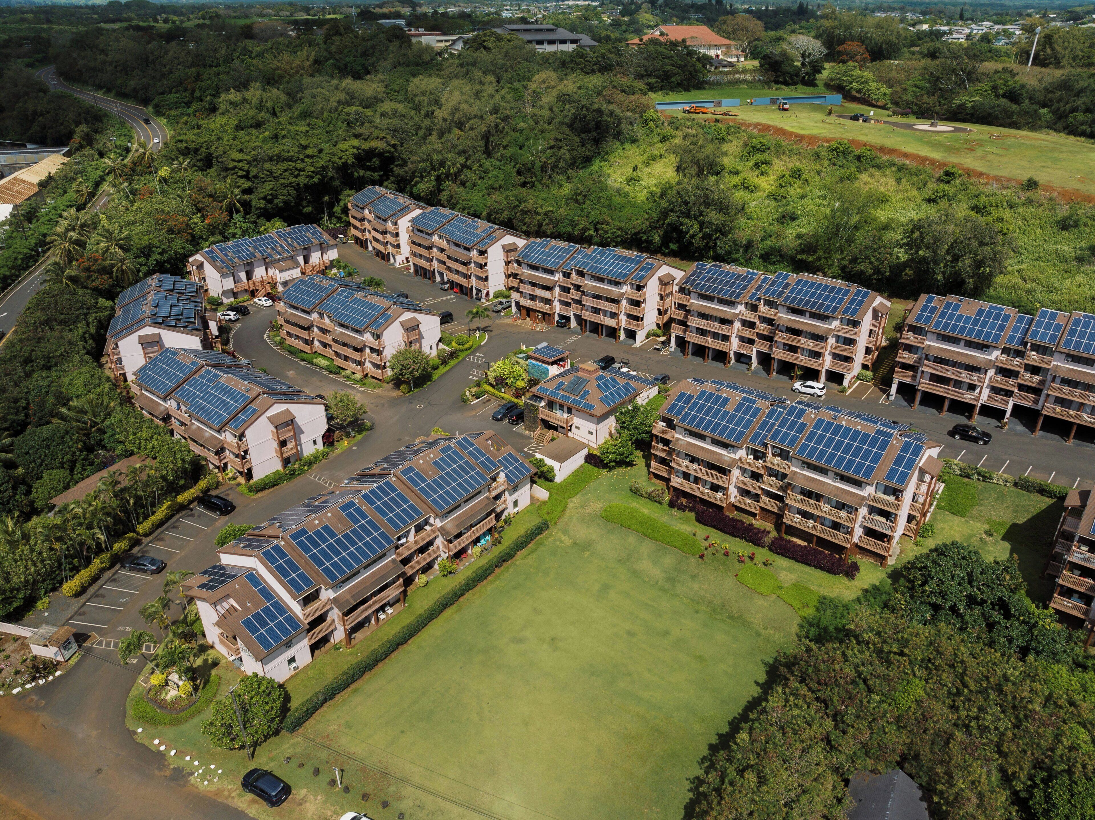 A residential complex with multiple buildings, each featuring solar panels on the roofs.