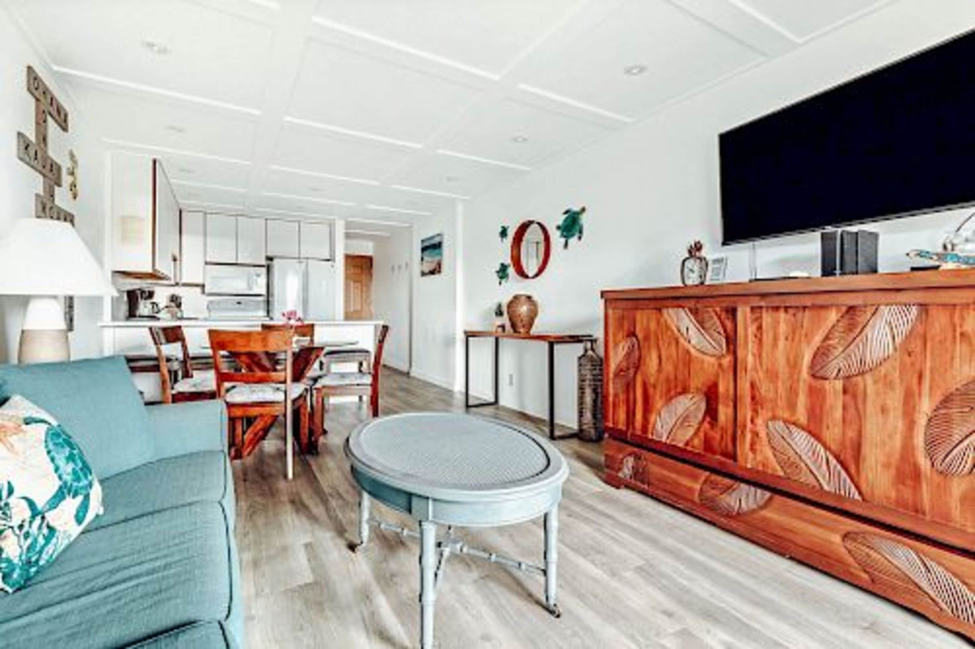 A modern living room with a sofa, a round table, a wooden cabinet, and a television.