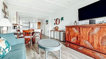 A modern living room with a sofa, a round table, a wooden cabinet, and a television.