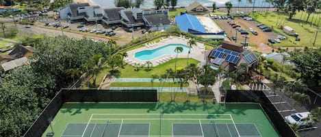 A tennis court with a pool and a view of the ocean.