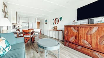 Una sala de estar con sofá, una mesa redonda, un armario de madera y televisión.