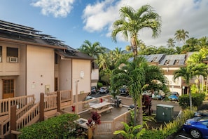 A residential building with solar panels, a covered parking area, and a view of palm trees. - Banyan Harbor Resort (Lihue)