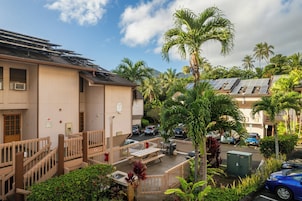 Un edificio residencial con paneles solares, zona de estacionamiento techada y vista a palmeras.