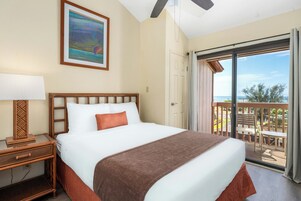 Habitación de hotel con cama, mesita de noche, lámpara, un cuadro y balcón con vistas.