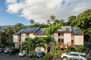 A building with solar panels on the roof, surrounded by palm trees and parked cars. - Banyan Harbor Resort (Lihue)