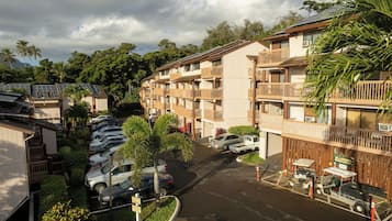 Ein mehrstöckiges Hotel mit Balkonen, Solaranlagen und einem Parkplatz mit Autos.
