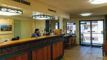 A reception area with a wooden counter, a receptionist, and a view of the outside through a glass door.