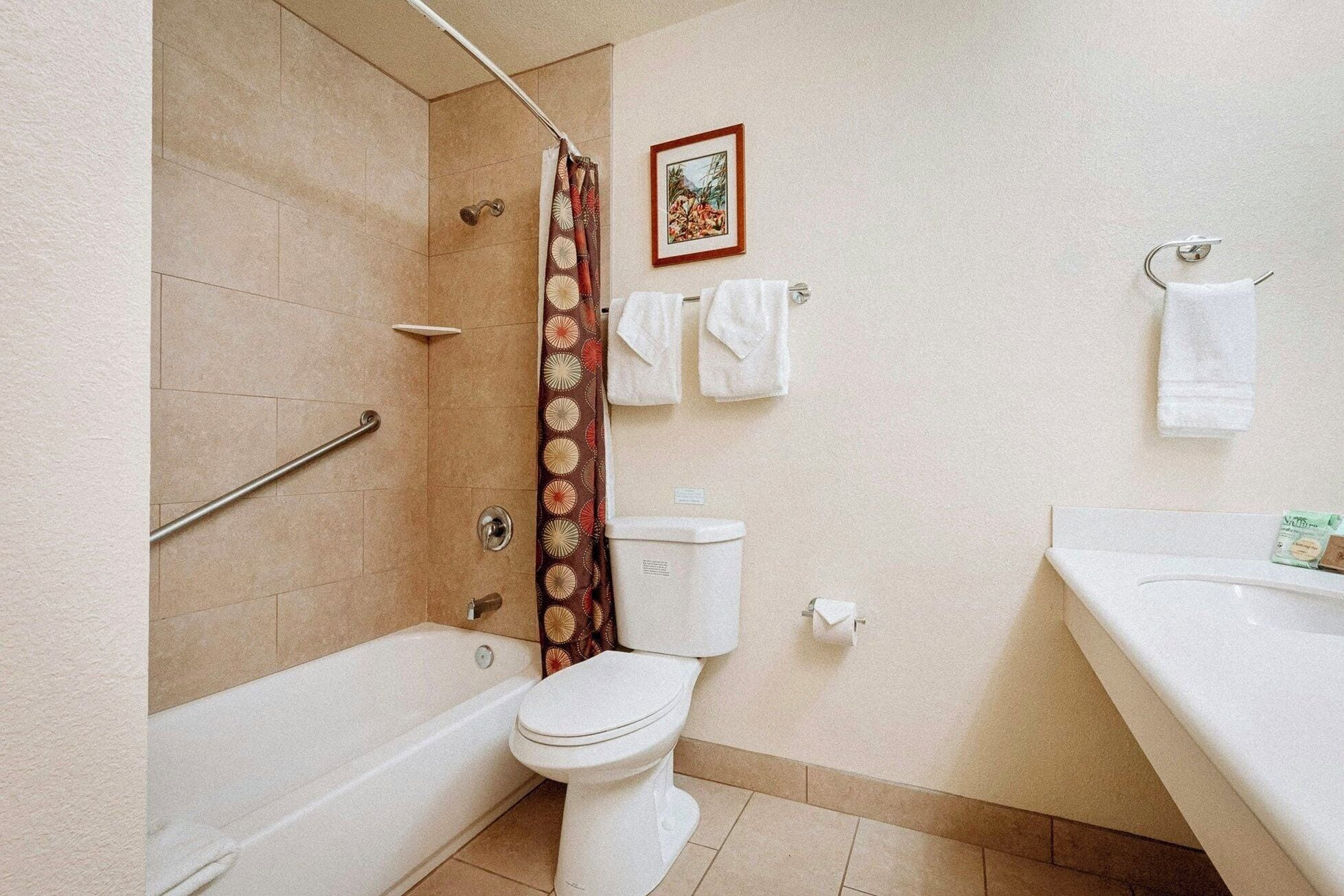 Un baño con bañera, inodoro, cortina de ducha y un perchero con toallas.