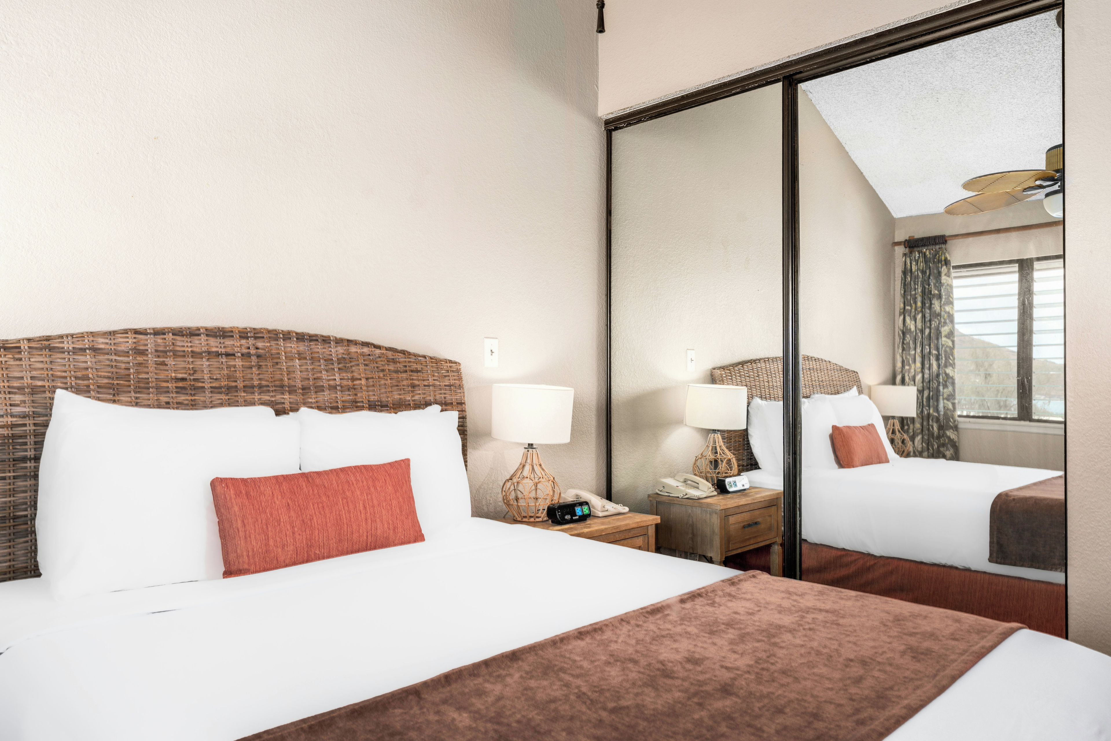 A hotel room with a large bed, two bedside tables with lamps, a mirror, and a view of the outside.