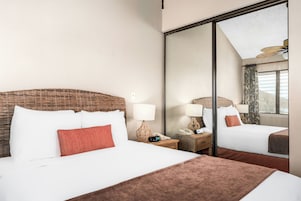Habitación de hotel con una cama grande, dos mesitas de noche con lámparas, un espejo y vistas al exterior.