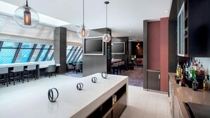 Un espace bar moderne doté d’un long comptoir, de luminaires suspendus et d’un bar bien garni de bouteilles.