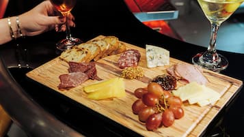 A wooden board with various cheeses, meats, and grapes.