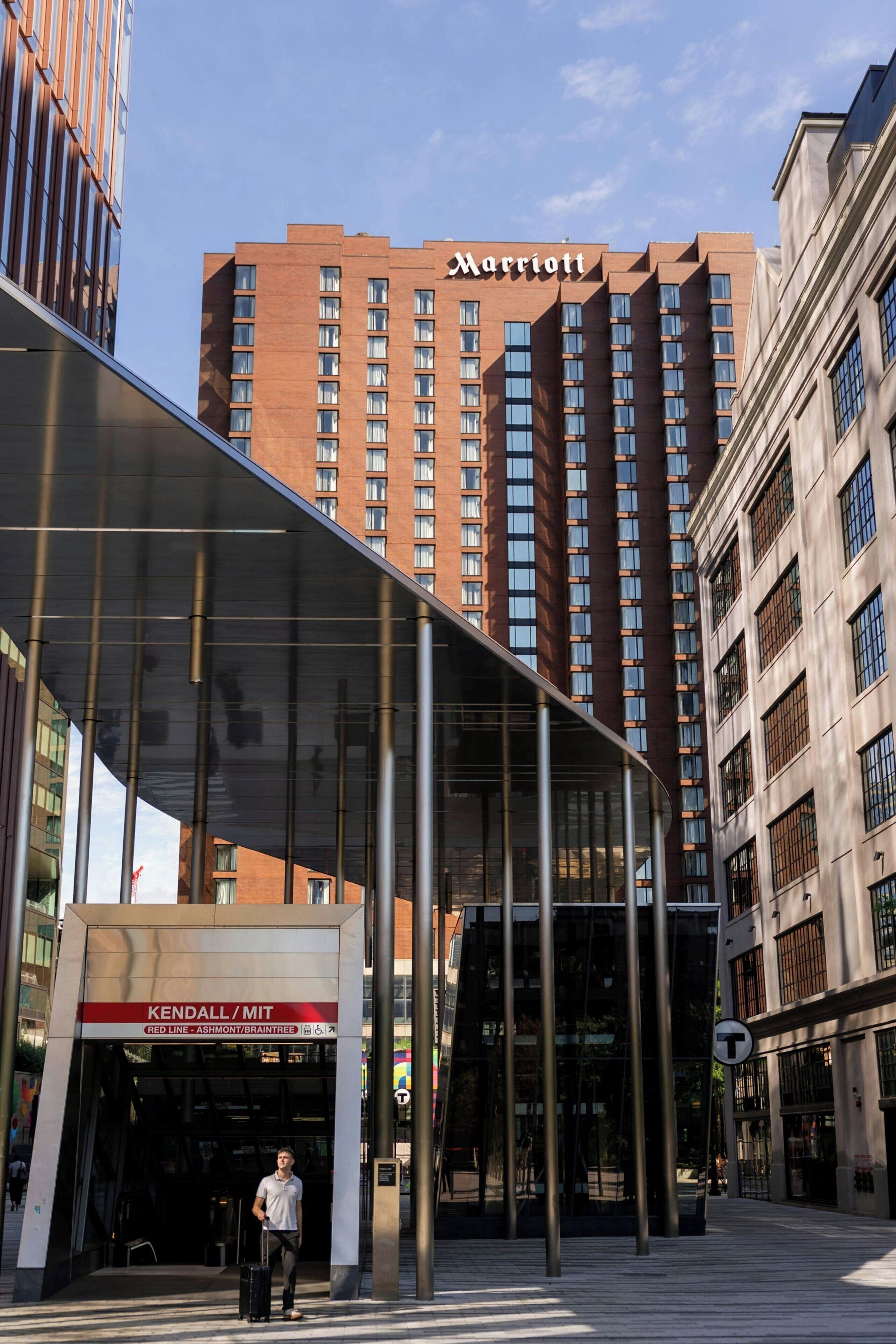 Una entrada de hotel moderna con una marquesina de vidrio, un letrero de Marriott y un letrero de Kendall/MT.