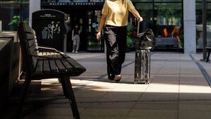 Une femme marchant avec une valise devant l’entrée d’un hôtel Marriott.